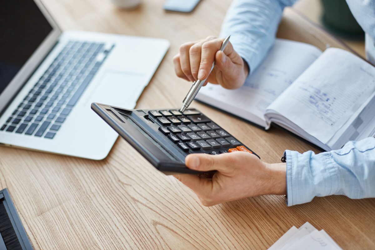 cropped-view-professional-serious-finance-manager-holding-calculator-hands-checking-company-month-s-profits-min